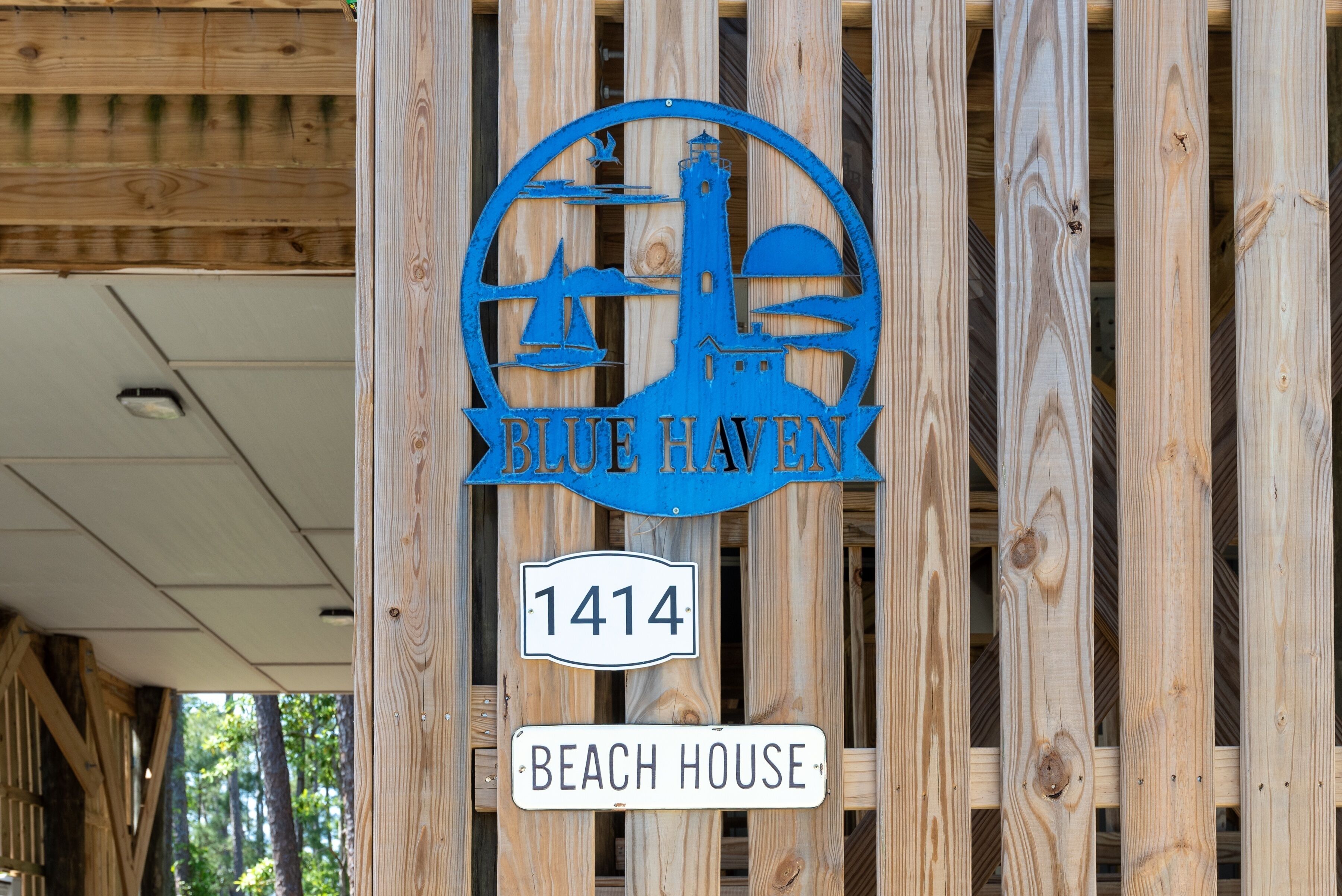 Un letrero de madera con un logotipo y el texto "Blue Haven 1414 Beach House".