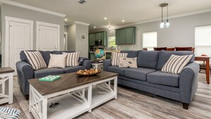 A living room with two grey sofas, a wooden coffee table, and a globe on a side table. - Blue Haven - 1414 Oleander 4 Bedroom Home by RedAwning (Dauphin Island)
