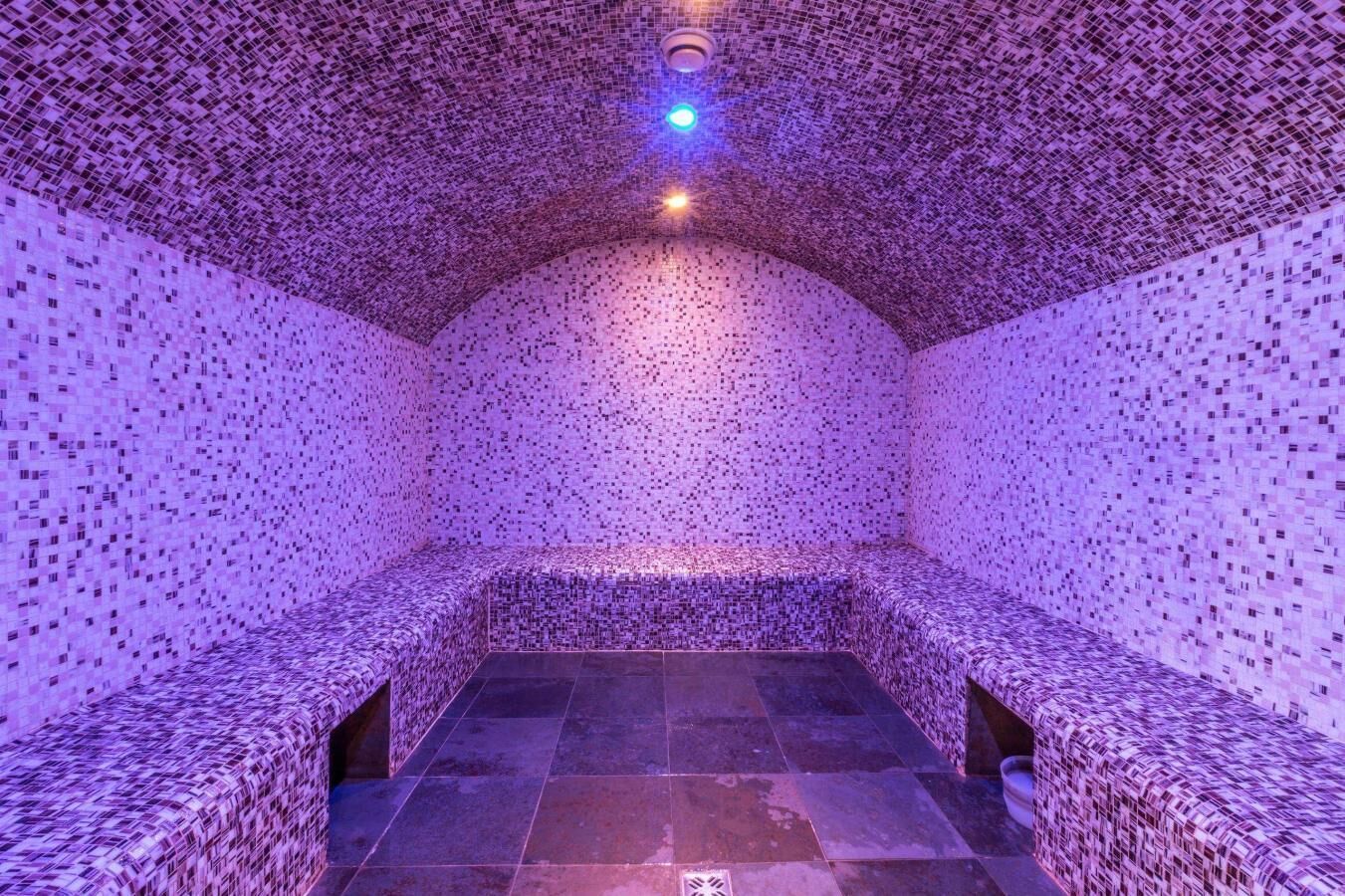 A room with a patterned ceiling and walls, a stone floor, and a bench along one wall.