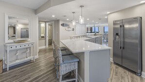 Una cucina moderna con una grande isola, elettrodomestici in acciaio inossidabile e vista sull'area living.