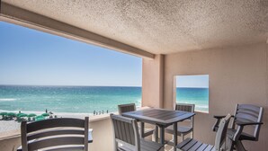 Un balcone con vista sull'oceano, un tavolo e quattro sedie.