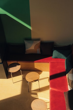 A modern interior with a sectional sofa, two small round tables, and a red accent wall. - Poppies (Amsterdam)