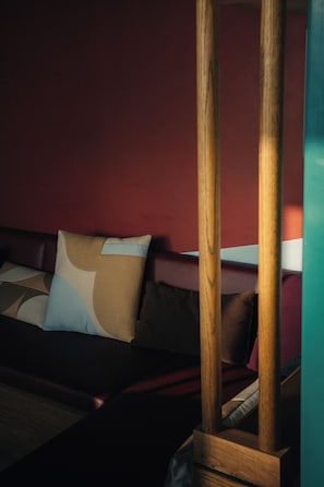 A room with a bed, a wooden headboard, and a red wall. - Poppies (Amsterdam)