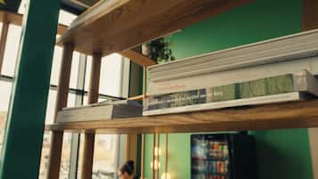 Una estantería con libros, un estante de madera y una ventana al fondo.