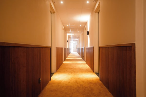 En lång, smal hall med träpanel på väggarna och ett heltäckningsmatta på golvet.