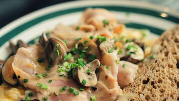 Una piastra di uova strapazzate con funghi e cipollotti, servita con fette di pane.