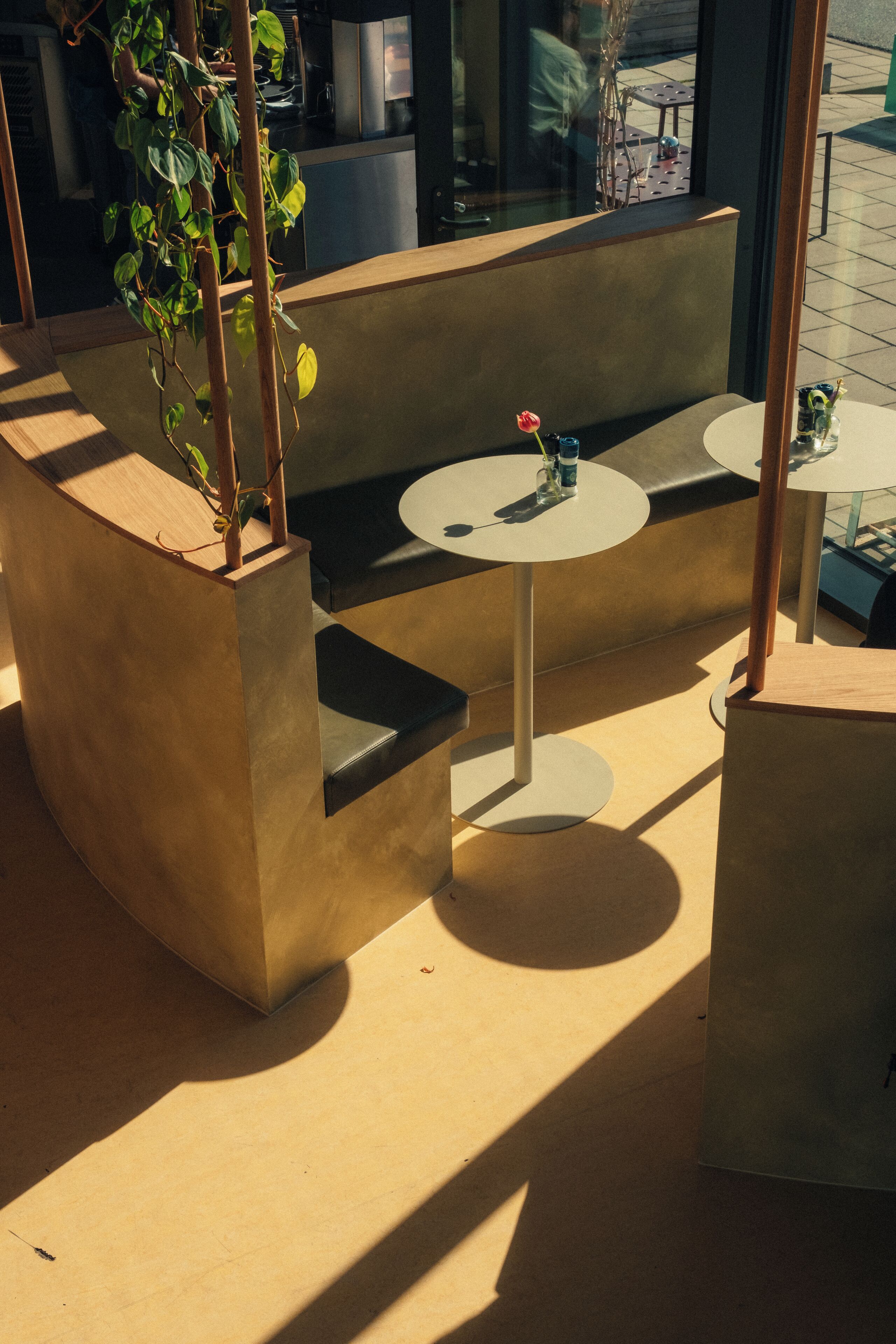 Un área de estar moderna al aire libre con un banco de concreto, una mesa redonda y una planta en maceta.