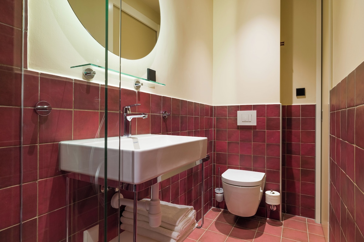 A modern bathroom with a glass shower enclosure, a white sink, and a toilet.