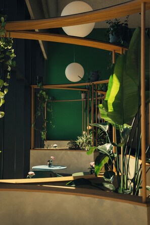 Une pièce avec un mur vert, un miroir rond et une étagère en bois ornée de plantes.