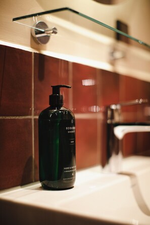 A bathroom with a green bottle of hand and body soap on a sink. - Poppies (Amsterdam)