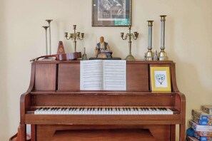 Een piano met bladmuziek, decoratieve objecten en een foto in een lijst op een standaard.
