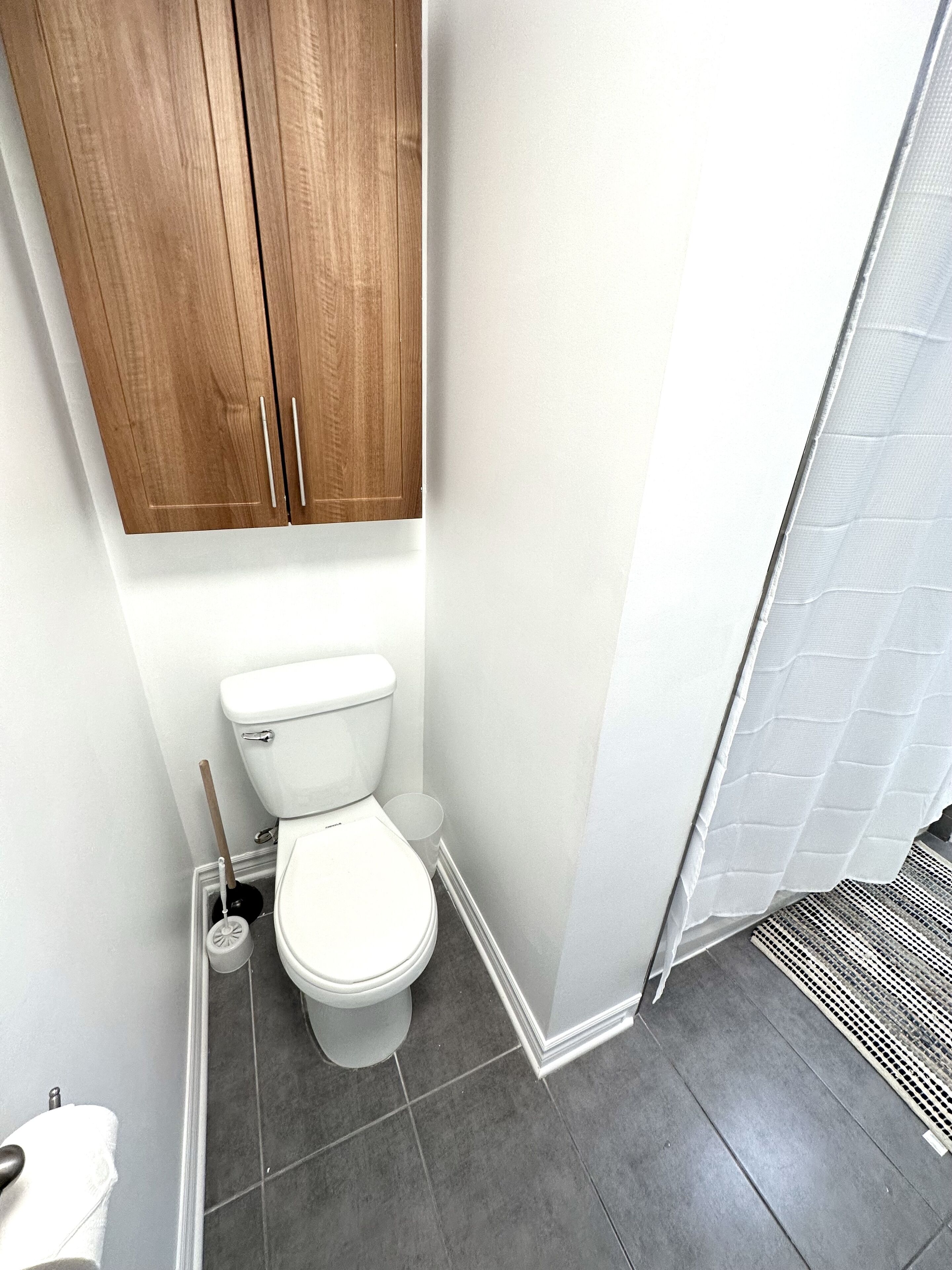 Une salle de bain comprenant des toilettes, un meuble en bois et un espace douche.