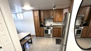 A modern kitchen with wooden cabinets, stainless steel appliances, and a large window. - The Extravagant Minimalist (Gatineau)