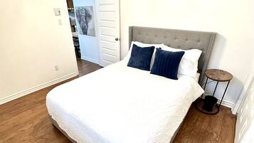A bedroom with a bed, a ceiling fan, and a door leading to another room.