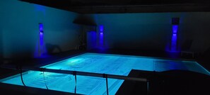 A large, rectangular pool with a glass bottom, surrounded by walls with vertical light fixtures.