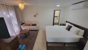 Une chambre d’hôtel avec un lit, un canapé, une petite table ronde et un miroir.