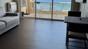 Una sala de estar moderna con sofá, televisor y balcón con vista al mar.
