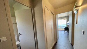 Un pasillo con vista a un balcón, una puerta que da a un baño y una lámpara en la pared.