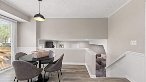 Une cuisine moderne avec un coin repas, comprenant une table ronde avec des chaises, un luminaire suspendu et un îlot de cuisine intégré avec des sièges.
