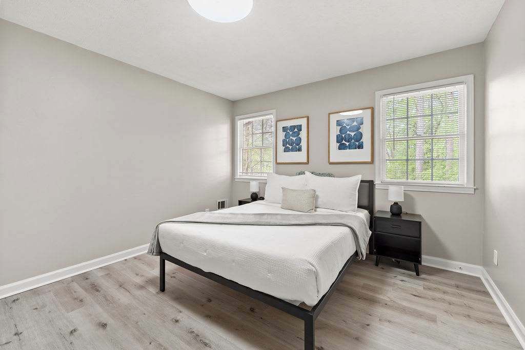 A bedroom with a bed, nightstands, and artwork on the wall.