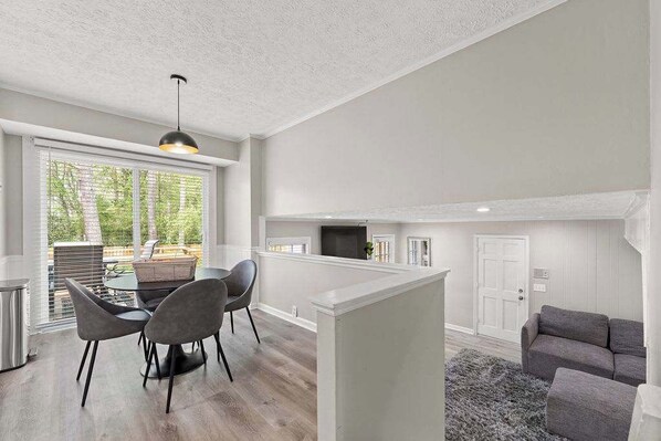 Une cuisine moderne dotée d’un îlot central, d’un coin repas avec des chaises et d’une grande fenêtre avec des stores.