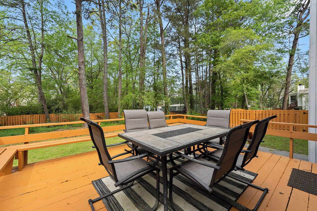 A deck with a table and chairs, surrounded by a wooden fence and trees.