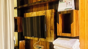 Une salle de bain avec un meuble-lavabo en bois, un téléviseur fixé au mur, un porte-serviettes et un calendrier.