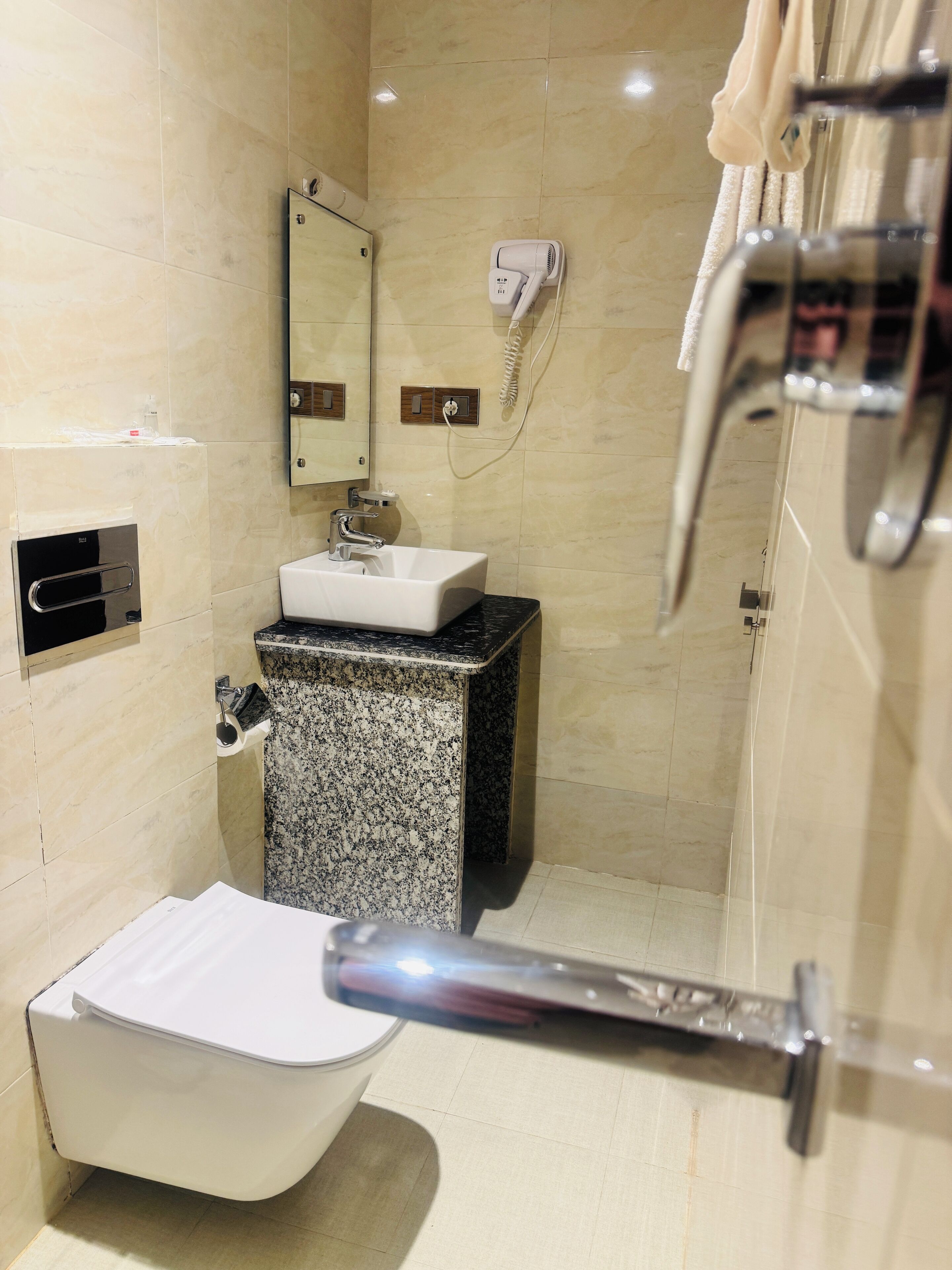 Un baño moderno con una bañera independiente, un lavamanos con encimera de granito, un perchero y un cabezal de ducha de mano.