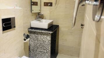 Un baño moderno con una bañera independiente, un lavamanos con encimera de granito, un perchero y un cabezal de ducha de mano.
