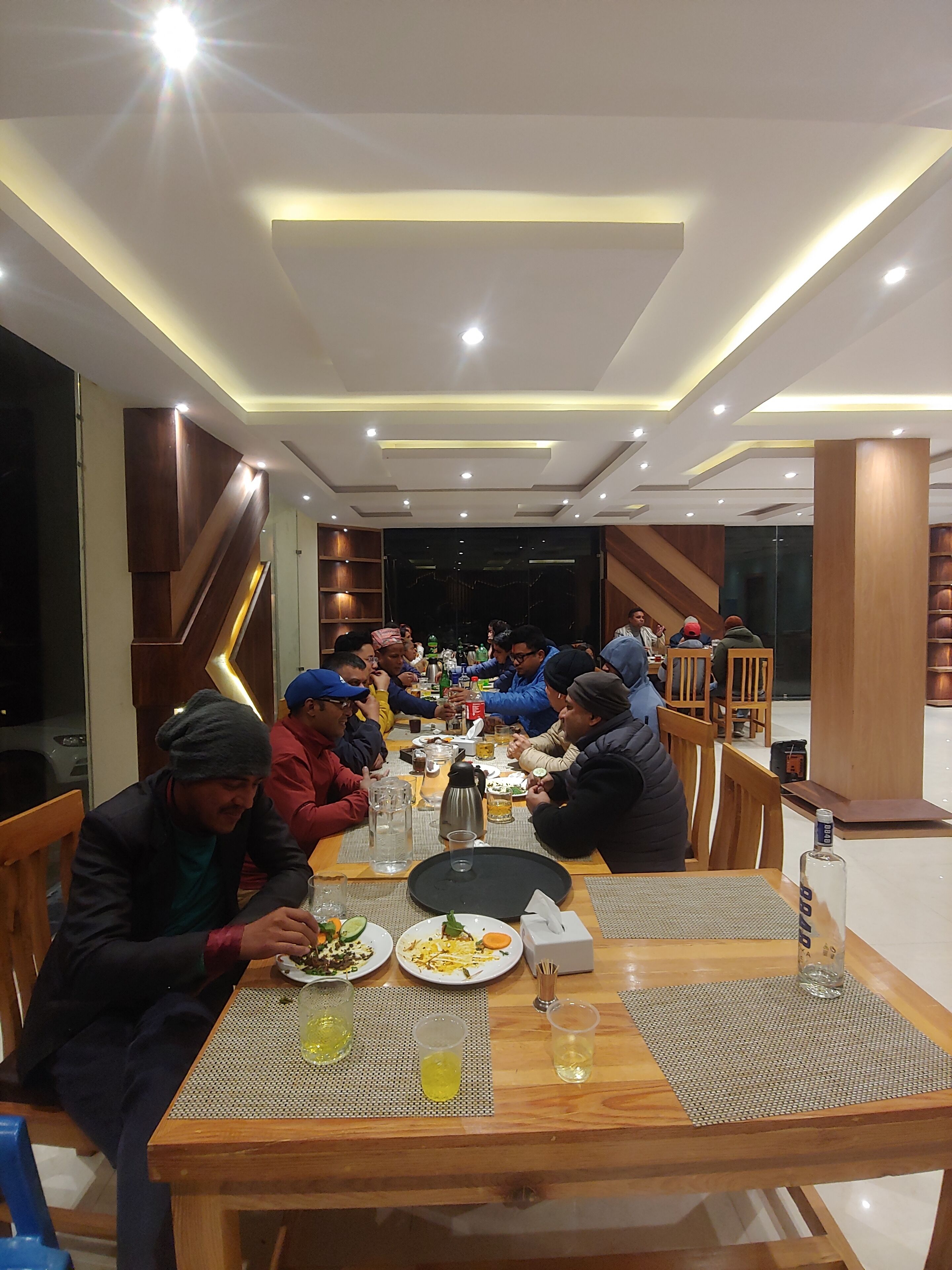 A dining area with a long table, multiple chairs, and a variety of dishes and drinks.