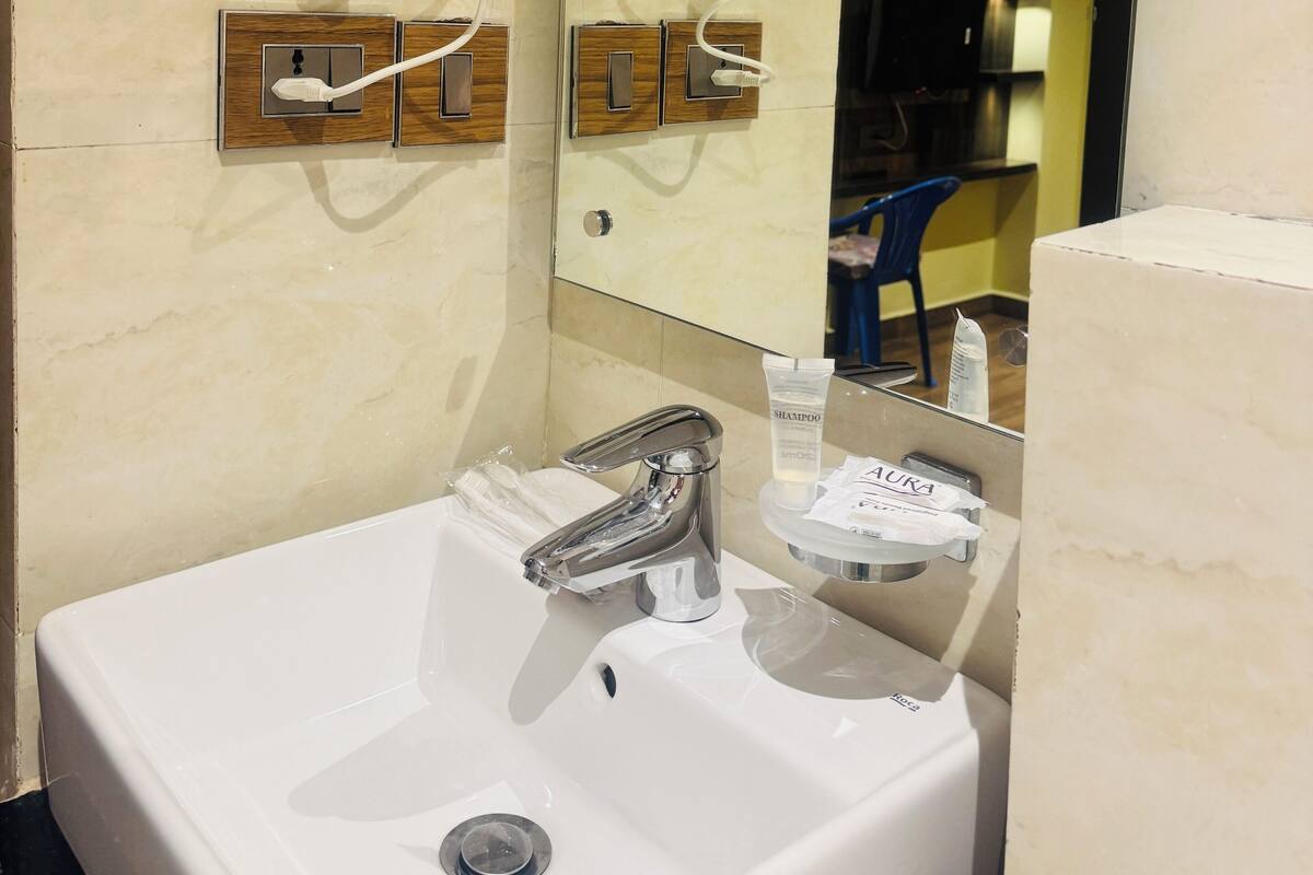 Un baño moderno con un lavabo blanco, un espejo, un secador de pelo y un dispensador de toallas.