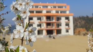 Un immeuble à étages, doté de nombreux balcons, se dressant sous un ciel d’un bleu limpide.
