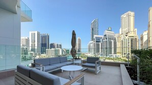A modern outdoor lounge area with seating and a view of a city skyline. - Stella Maris Tower (Dubai)