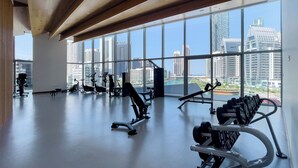 A gym with exercise equipment and large windows offering a city view. - Stella Maris Tower (Dubai)