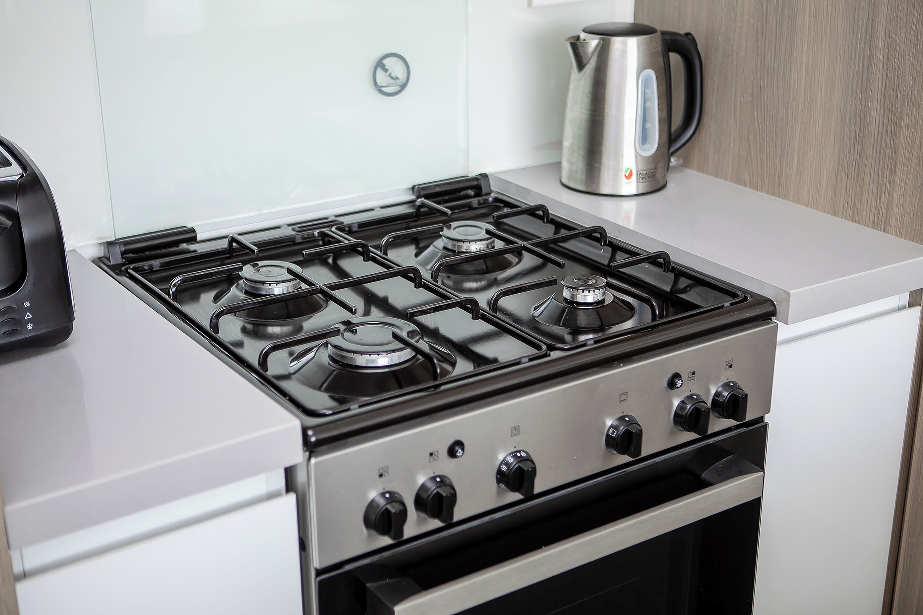 A modern kitchen with a stainless steel stove, a kettle, and a toaster.