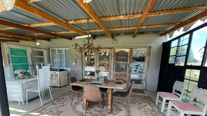 Un comedor rústico con una mesa y sillas de madera, una araña y vistas a través de amplios ventanales.