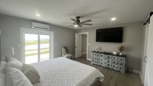 Un dormitorio con cama, cómoda, ventilador de techo y televisor en la pared.