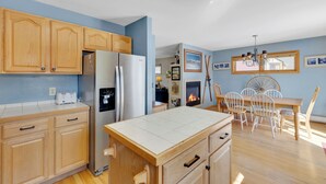 A kitchen with wooden cabinets, a refrigerator, a dining table with chairs, and a fireplace. - Views! Private 4 Bedroom Home with Private Hot Tub!!! (Breckenridge)