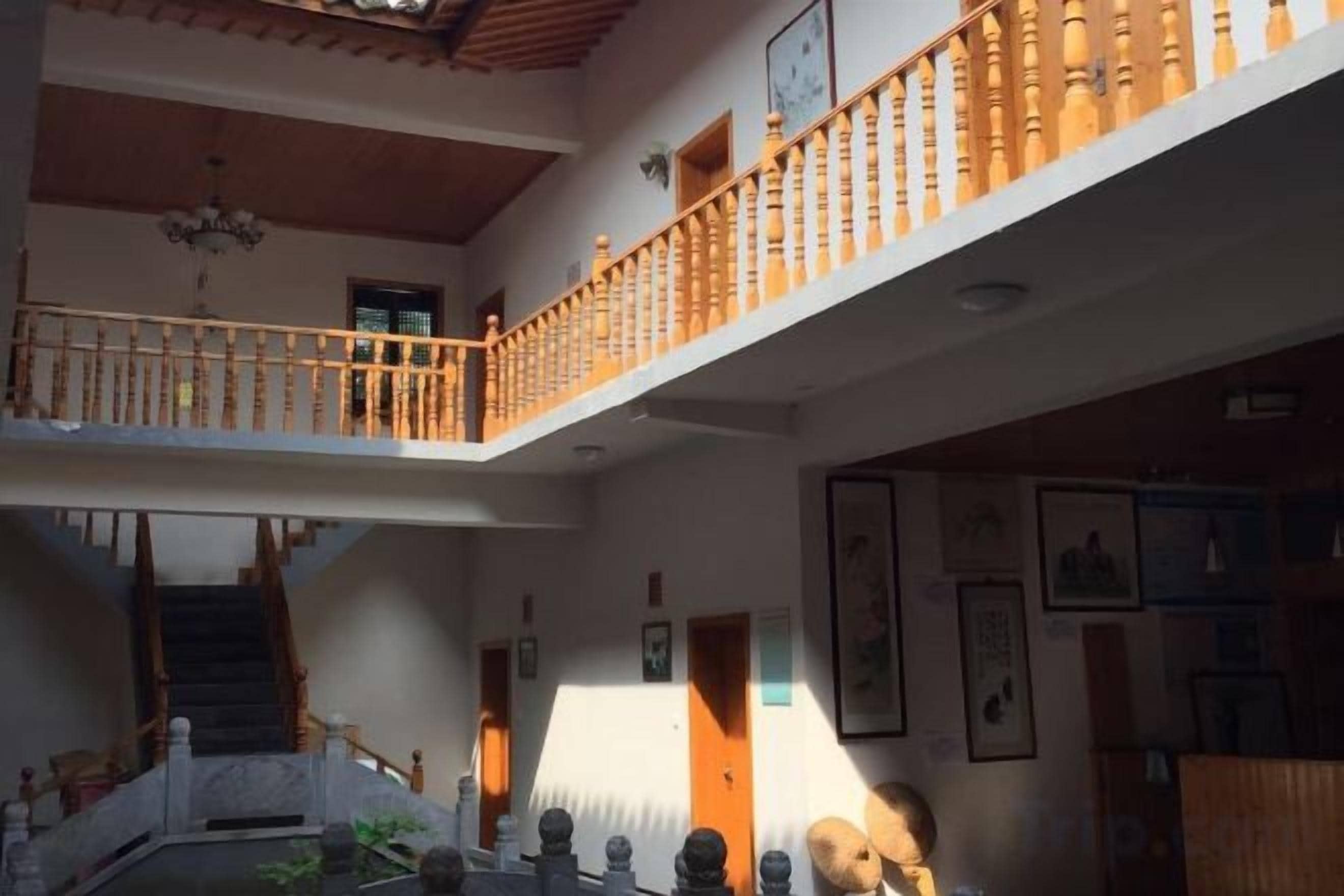 A multi-level interior with a staircase, wooden railings, and a chandelier.