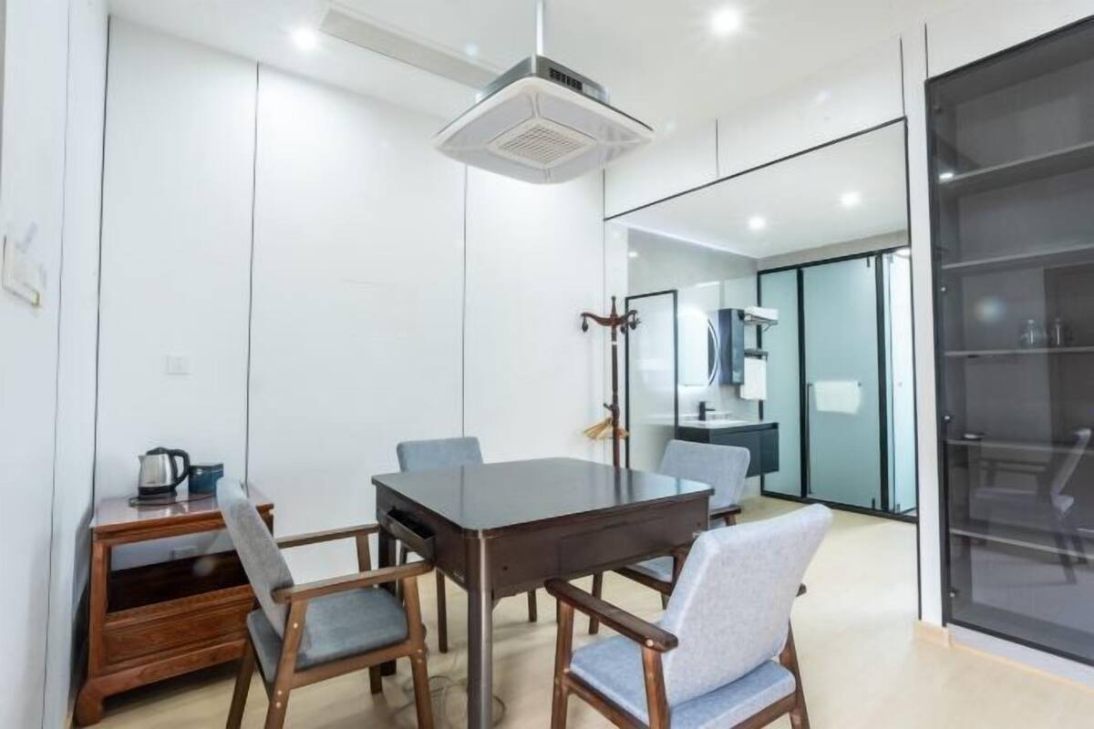 Una sala de reuniones moderna con una mesa de madera oscura, dos sillas grises, una mesita auxiliar de madera con una tetera y un purificador de aire instalado en el techo.