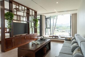 A modern living room with a TV, wooden cabinet, sofa, and large windows. - Liuxi Hostel (Jing County)