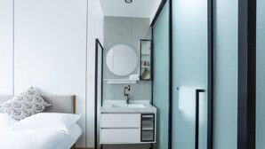 Un dormitorio moderno con cama, mesita de noche, espejo y armario empotrado.