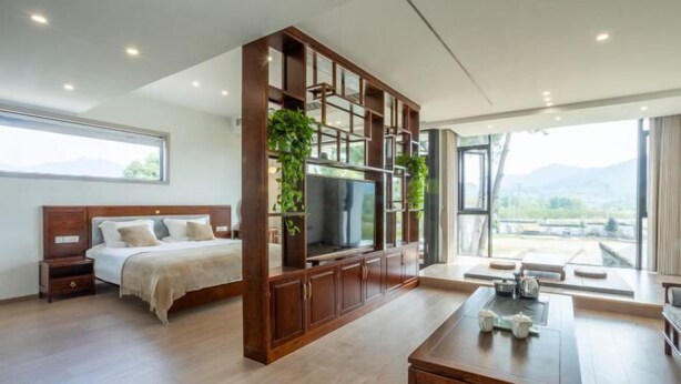 Ein modernes Schlafzimmer mit einem großen Bett, einem Fernseher und einer Holzkabine mit Pflanzen.
