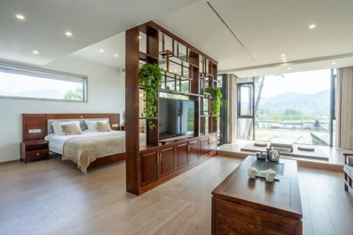 Un dormitorio moderno con una cama grande, un televisor y un mueble de madera con plantas.