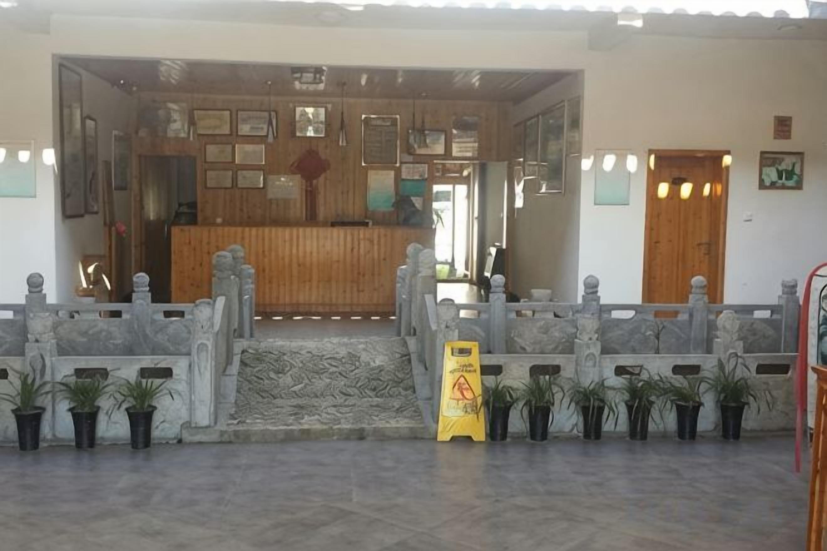 Zona de recepción con un escritorio de madera, mostrador de recepción y una escalera que sube a un nivel superior.