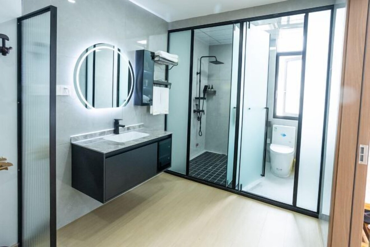 A modern bathroom with a glass-enclosed shower, a vanity with a mirror, and a toilet.