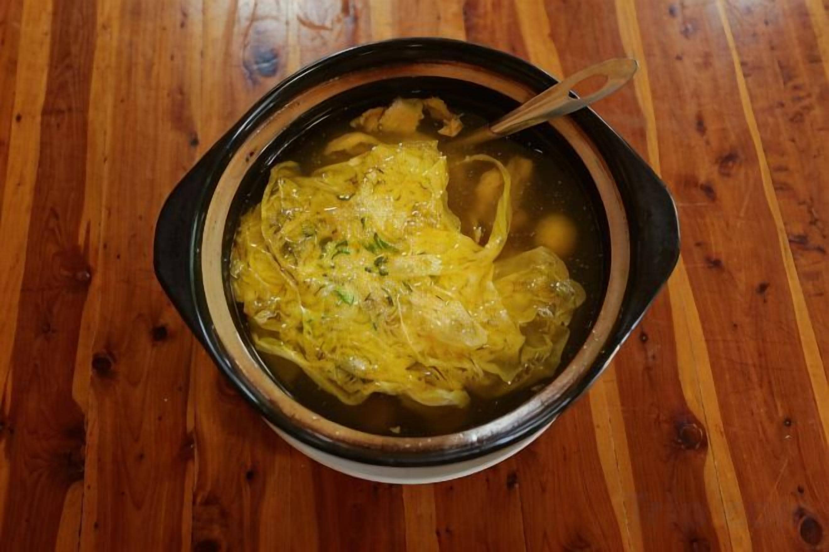 A bowl of soup on a wooden table.