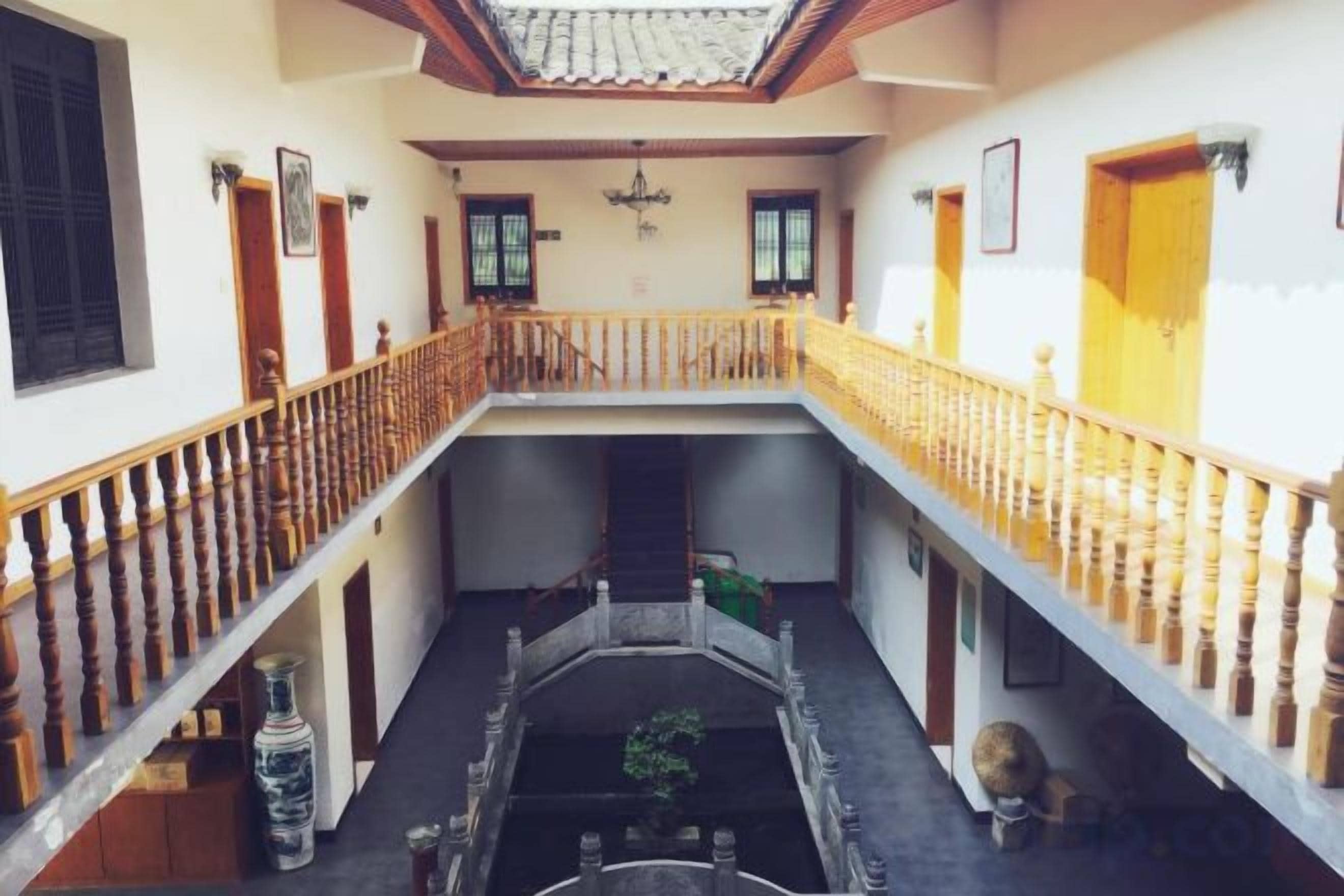 A multi-level interior with a central courtyard, wooden railings, and a tiled ceiling.