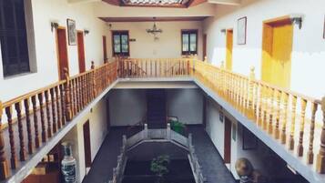 A multi-level interior with a central courtyard, wooden railings, and a tiled ceiling.