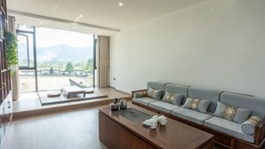 Ein modernes Wohnzimmer mit Sofa, Couchtisch und Blick ins Freie.